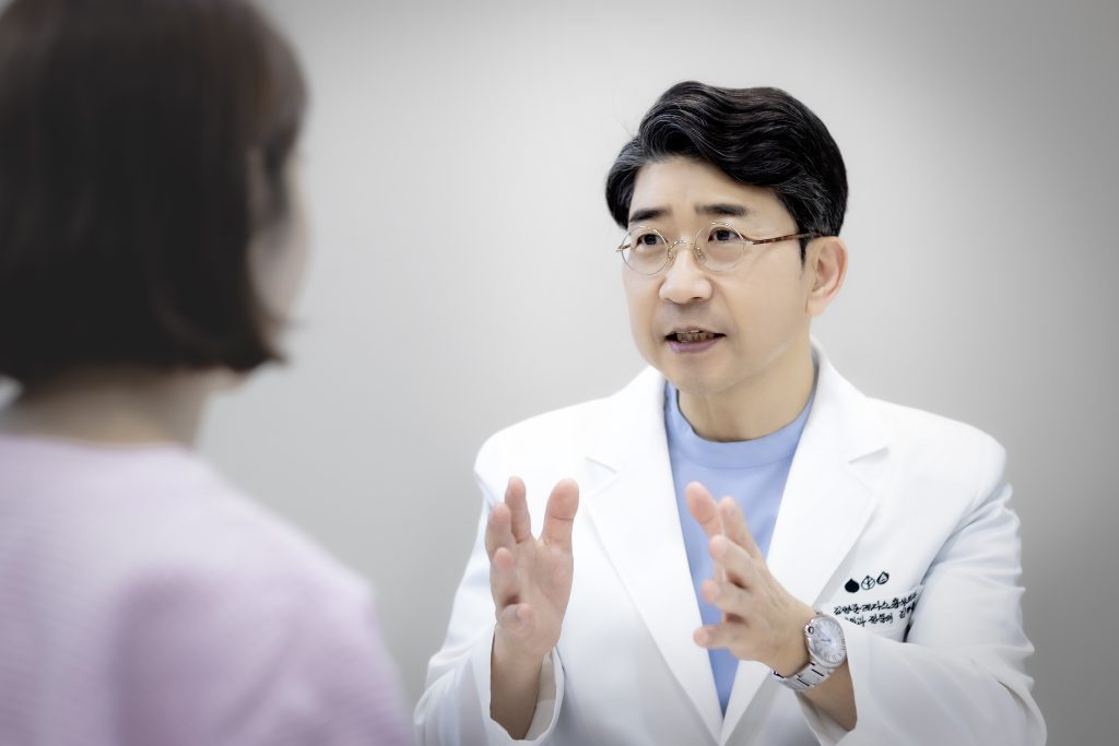 편안한 표정으로 진료실 의자에 앉아 원장님과 웃으며 정기검진 상담을 하는 환자